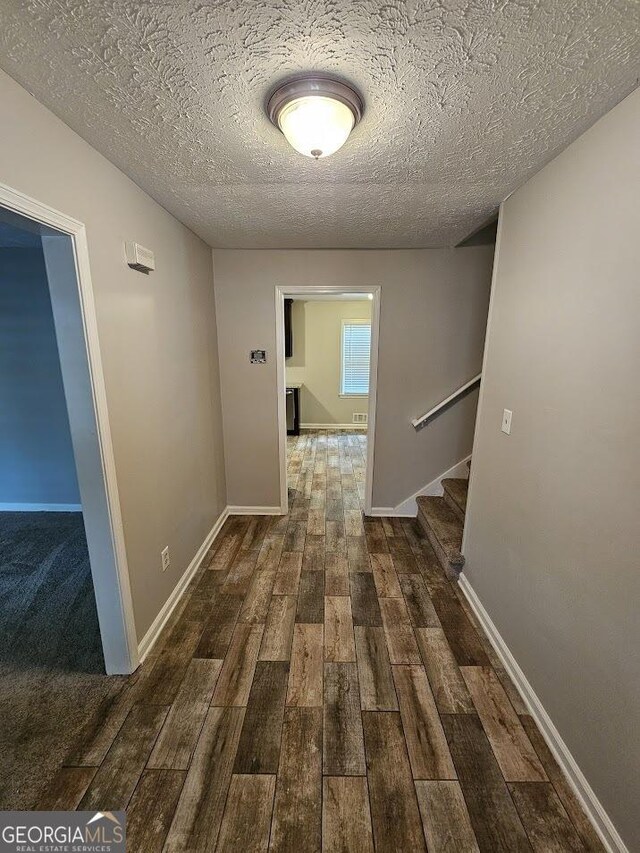 hallway with dark hardwood / wood-style flooring and a textured ceiling