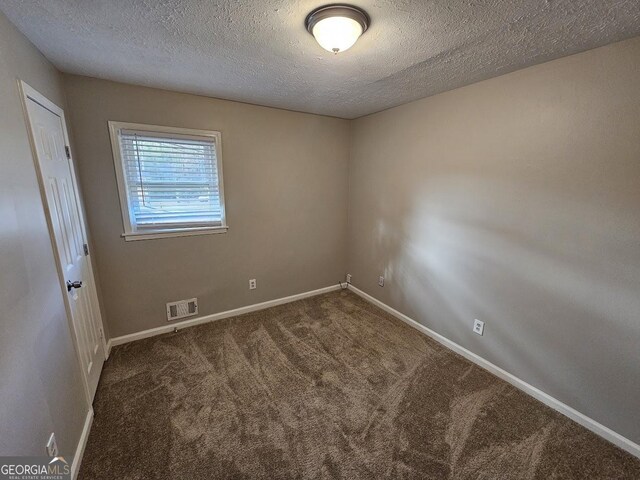 unfurnished room featuring dark carpet and a textured ceiling