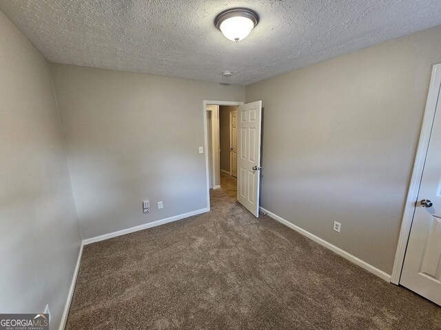 unfurnished room featuring carpet and a textured ceiling