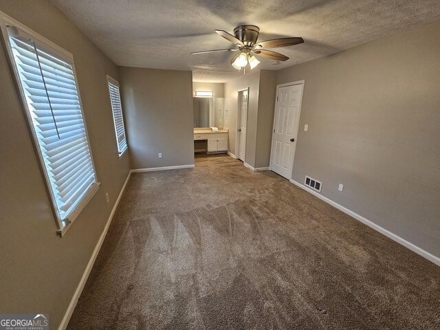 unfurnished bedroom featuring carpet, ensuite bathroom, ceiling fan, and a textured ceiling