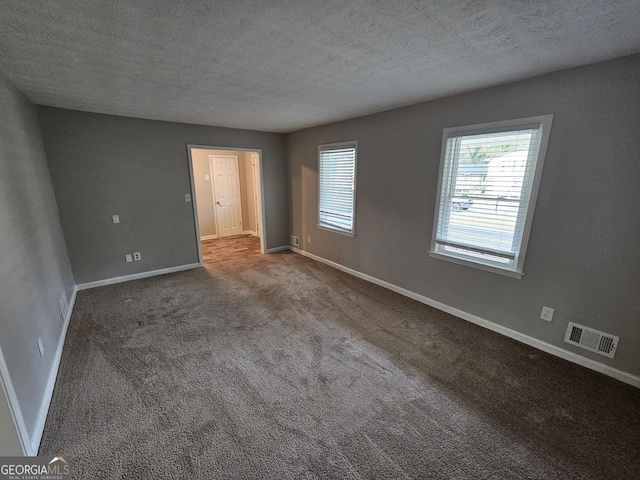 carpeted empty room featuring a textured ceiling