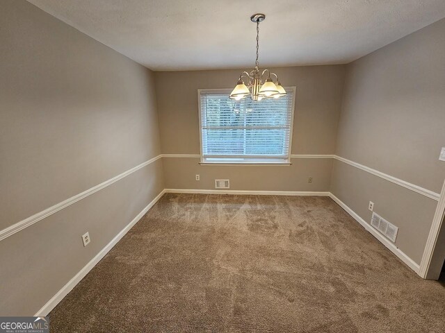 carpeted spare room with a textured ceiling and a chandelier