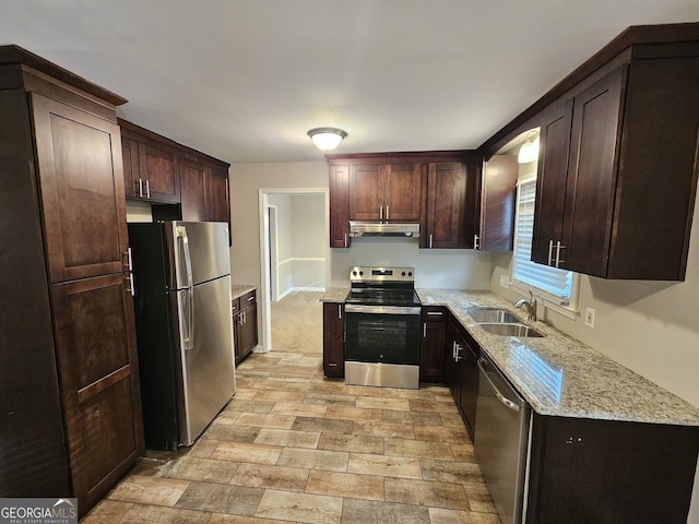 kitchen with light stone counters, sink, stainless steel appliances, and dark brown cabinets