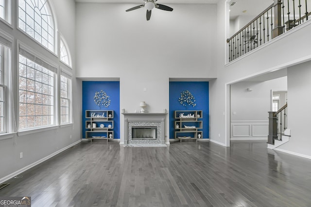 living room with a fireplace, a towering ceiling, dark hardwood / wood-style floors, and ceiling fan