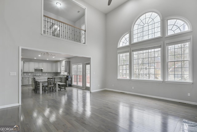 living room featuring ceiling fan, wood-type flooring, and a towering ceiling