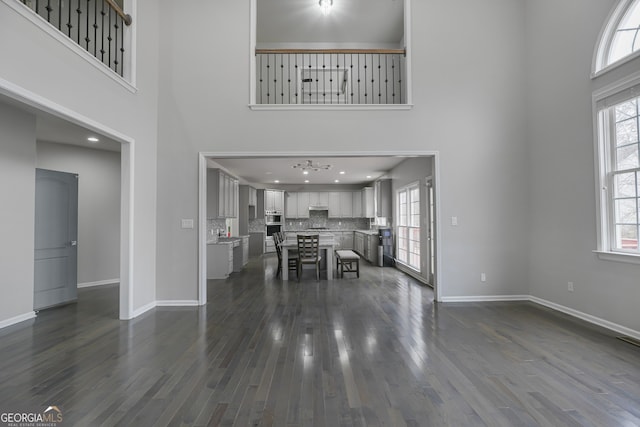 unfurnished living room featuring dark hardwood / wood-style flooring and a towering ceiling