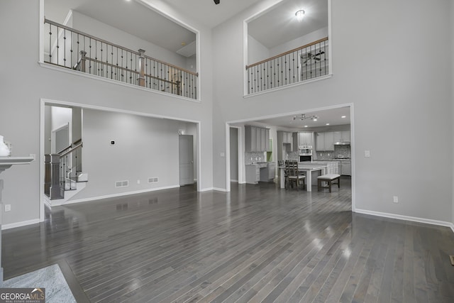 unfurnished living room featuring a chandelier, a high ceiling, and dark wood-type flooring