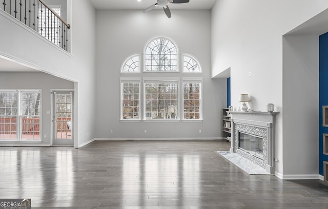 living room featuring a wealth of natural light, a premium fireplace, dark wood-type flooring, and a towering ceiling