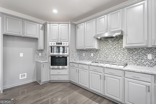 kitchen featuring dark hardwood / wood-style flooring, light stone countertops, stainless steel appliances, and tasteful backsplash