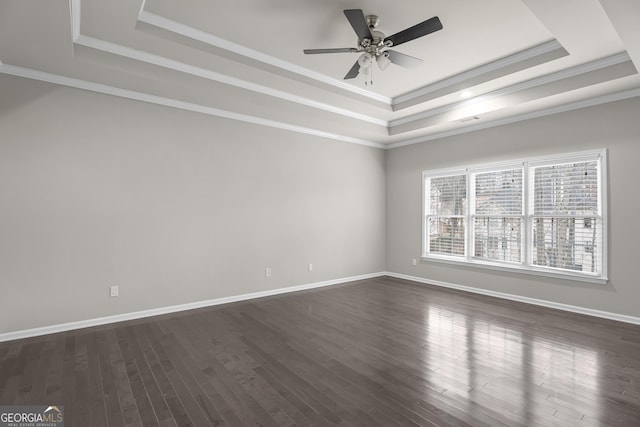 unfurnished room with a raised ceiling, ceiling fan, dark hardwood / wood-style flooring, and ornamental molding