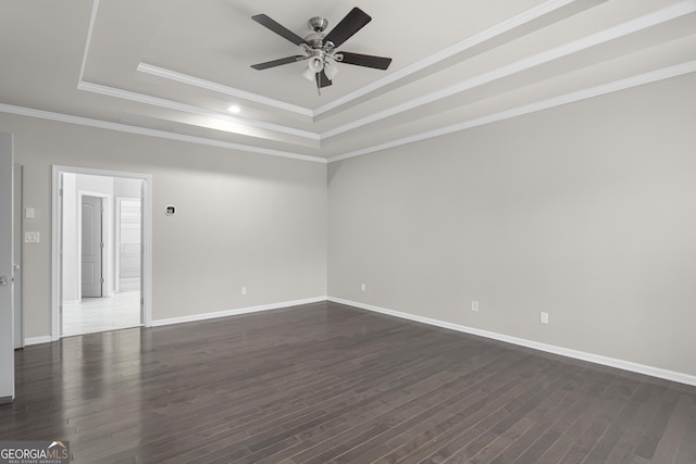 spare room with dark hardwood / wood-style flooring, a tray ceiling, ceiling fan, and ornamental molding