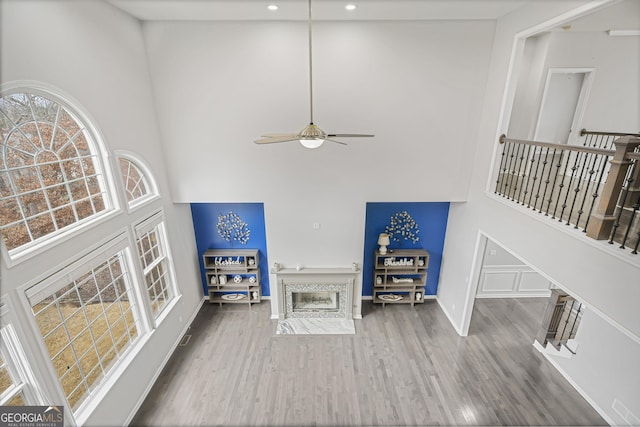 living room with a towering ceiling, hardwood / wood-style flooring, and ceiling fan