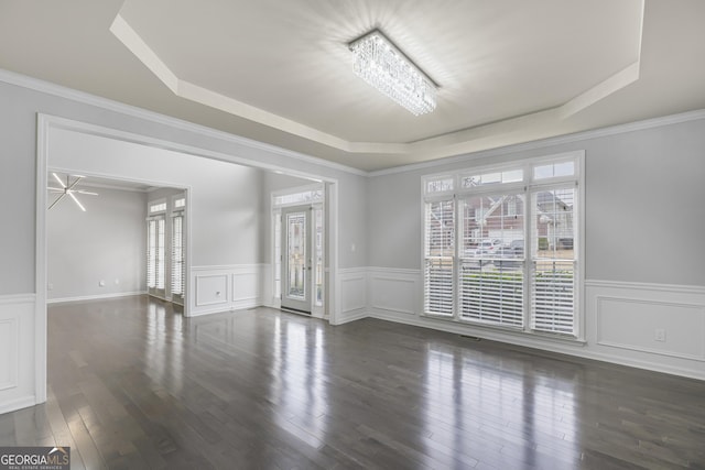 unfurnished room featuring a tray ceiling, crown molding, a chandelier, and dark hardwood / wood-style floors