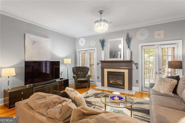 living room featuring french doors, light hardwood / wood-style floors, a notable chandelier, and ornamental molding