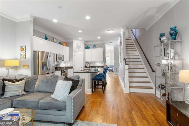 living room with light wood-type flooring, ornamental molding, and sink