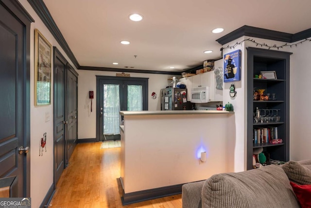 kitchen with stainless steel refrigerator, white cabinetry, kitchen peninsula, crown molding, and light wood-type flooring