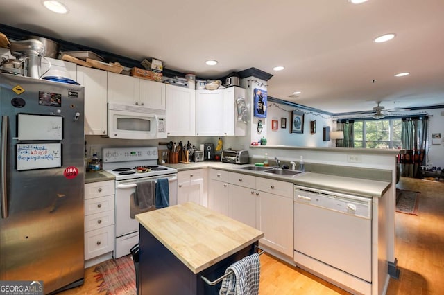 kitchen with white appliances, a kitchen island, ceiling fan, sink, and white cabinetry