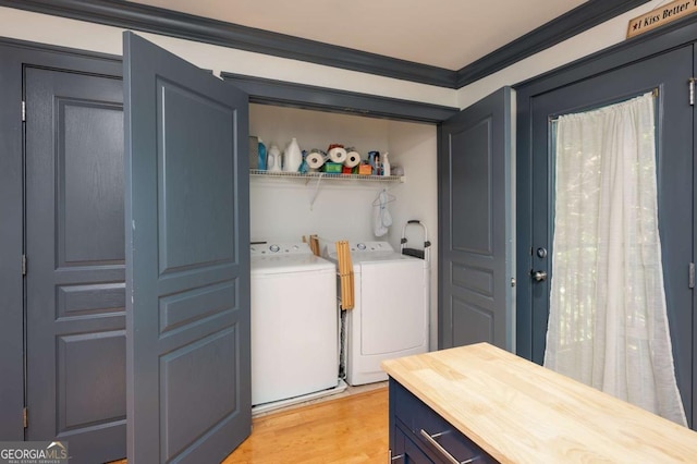 laundry room with light wood-type flooring, ornamental molding, and washing machine and clothes dryer