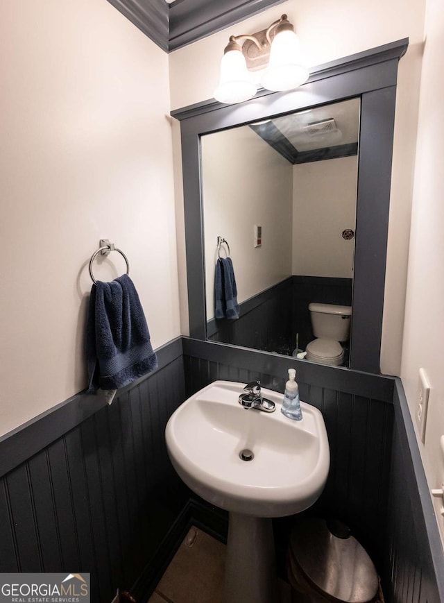 bathroom featuring toilet, crown molding, and sink