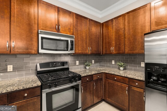 kitchen with ornamental molding, light stone countertops, stainless steel appliances, and tasteful backsplash