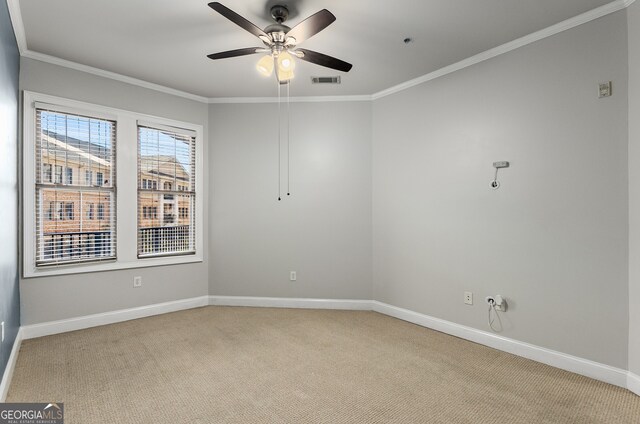 spare room featuring light carpet, ceiling fan, and crown molding