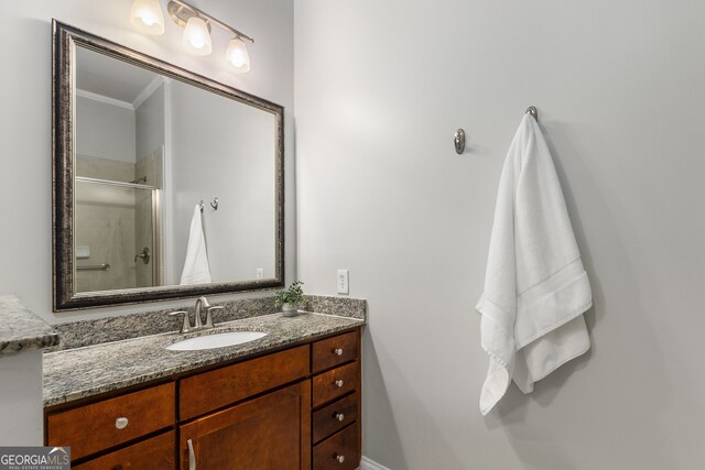 bathroom featuring vanity, a shower with shower door, and ornamental molding