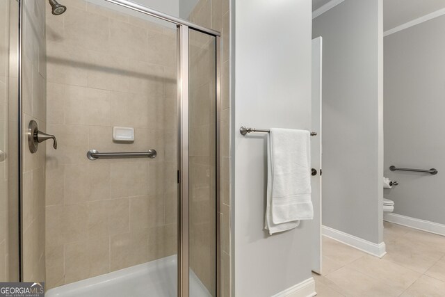 bathroom with tile patterned flooring, toilet, a shower with door, and crown molding