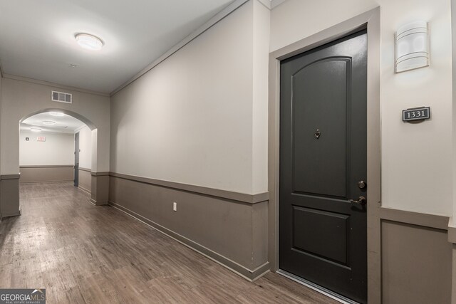 hall featuring wood-type flooring and crown molding