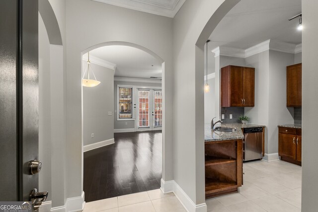 hallway with light tile patterned floors, ornamental molding, and sink