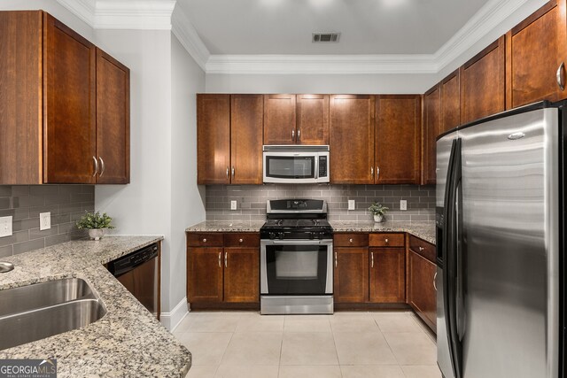 kitchen featuring light stone countertops, backsplash, ornamental molding, stainless steel appliances, and light tile patterned floors