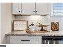 bar featuring dishwasher and white cabinetry