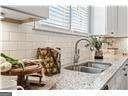 kitchen with light stone countertops, white cabinetry, and sink