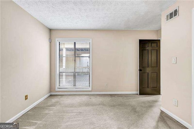 spare room with light colored carpet and a textured ceiling