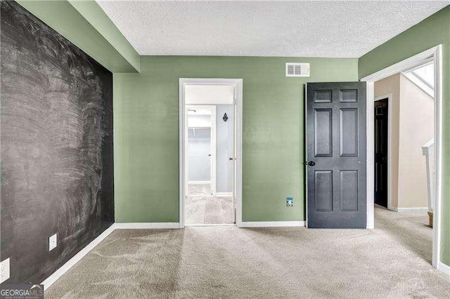 unfurnished bedroom with carpet flooring, a textured ceiling, and a spacious closet