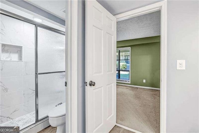 bathroom with toilet, a textured ceiling, and walk in shower