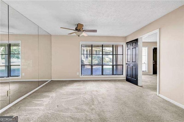 spare room with a textured ceiling, carpet floors, plenty of natural light, and ceiling fan