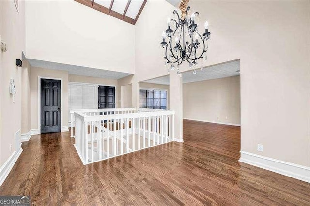 spare room featuring dark hardwood / wood-style flooring, high vaulted ceiling, and an inviting chandelier