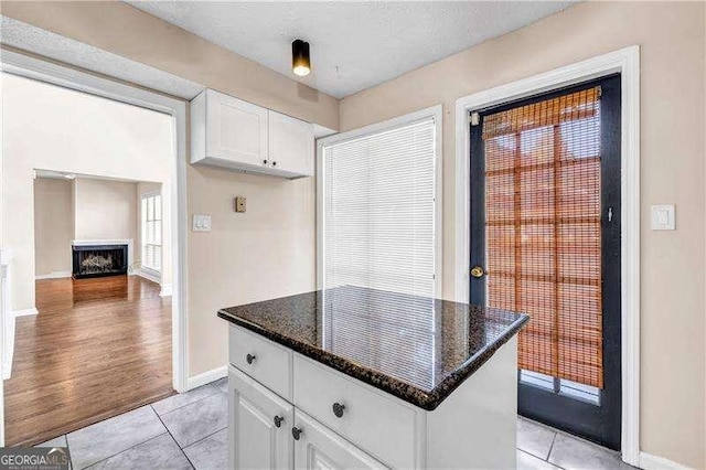 kitchen featuring dark stone countertops, white cabinets, and light tile patterned flooring