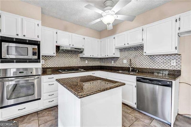 kitchen with sink, a kitchen island, dark stone countertops, white cabinets, and appliances with stainless steel finishes