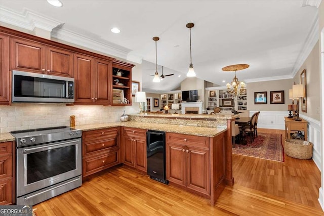 kitchen with ceiling fan with notable chandelier, kitchen peninsula, stainless steel appliances, and hanging light fixtures