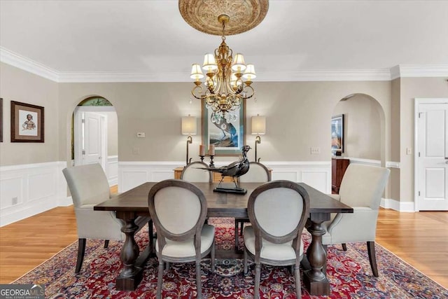 dining room with light hardwood / wood-style flooring, an inviting chandelier, and ornamental molding