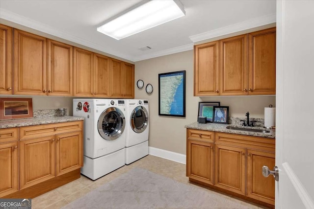 washroom featuring cabinets, crown molding, sink, washing machine and clothes dryer, and light tile patterned flooring