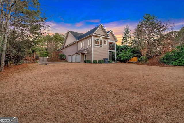 property exterior at dusk featuring central AC and a garage