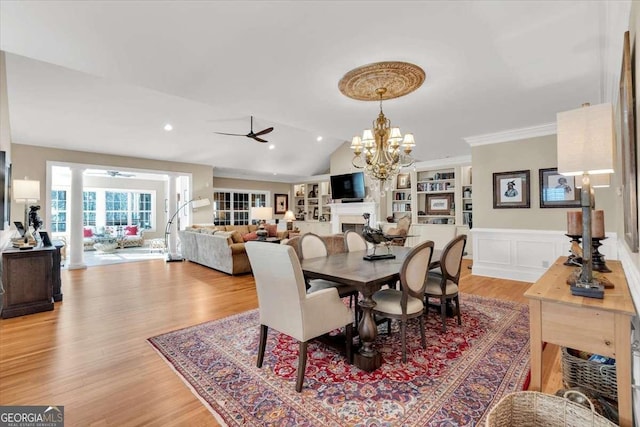 dining room featuring light wood-type flooring, ceiling fan with notable chandelier, and vaulted ceiling