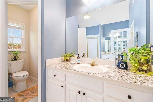 bathroom with tile patterned flooring, vanity, toilet, and a shower with shower door