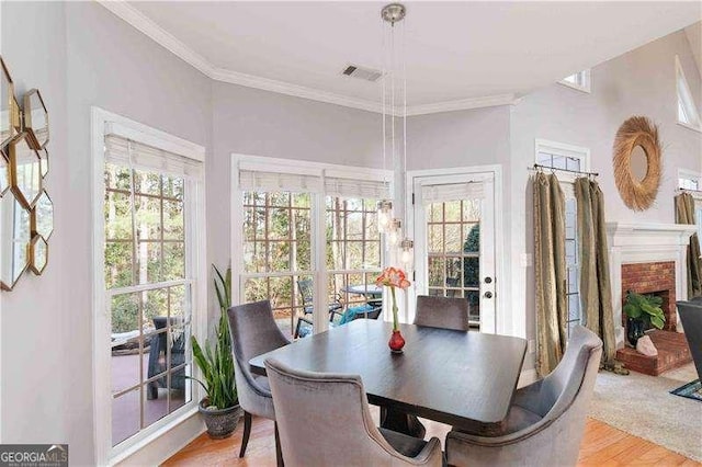 dining room with light hardwood / wood-style floors, ornamental molding, and a brick fireplace