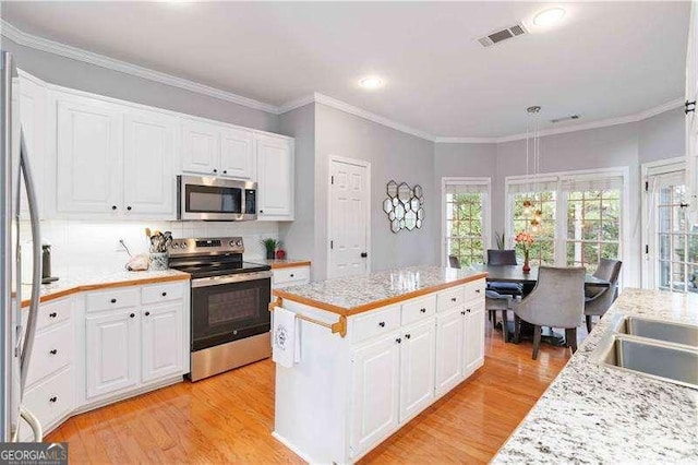 kitchen featuring ornamental molding, white cabinets, stainless steel appliances, and a kitchen island