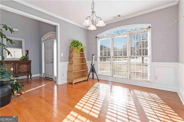 interior space featuring hardwood / wood-style flooring, a notable chandelier, and crown molding