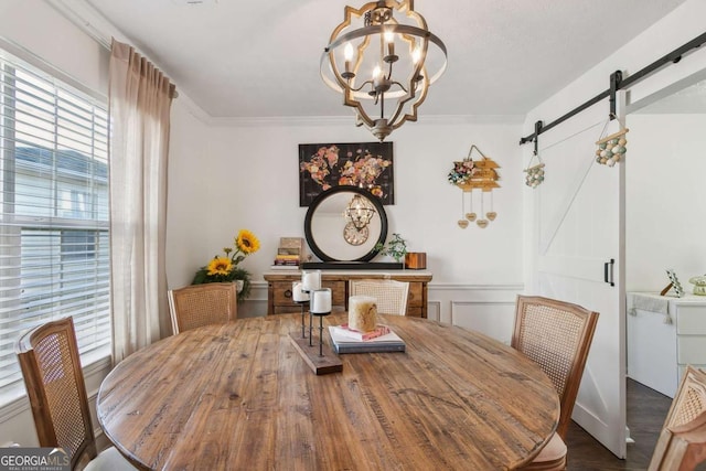 dining space featuring a barn door, crown molding, a healthy amount of sunlight, and an inviting chandelier