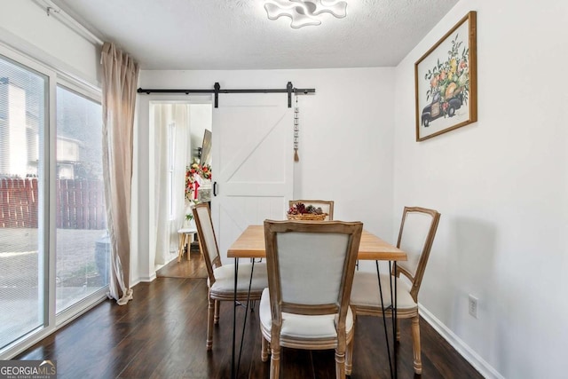 dining space with a textured ceiling, a barn door, dark hardwood / wood-style floors, and a wealth of natural light